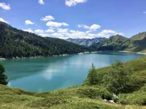 Vista panoramica sul Lago Ritom con acque turchesi, foreste alpine e vette della Val Piora