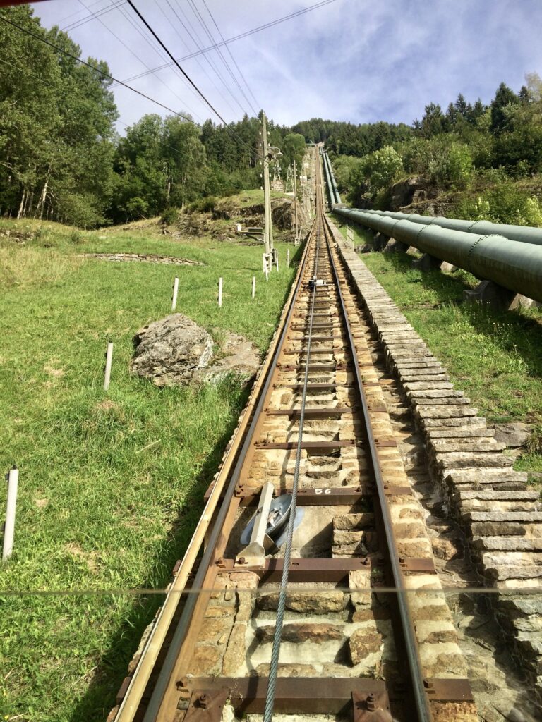 Tracciato ripido della Funicolare Ritom tra i pascoli verdi della Val Piora, Canton Ticino