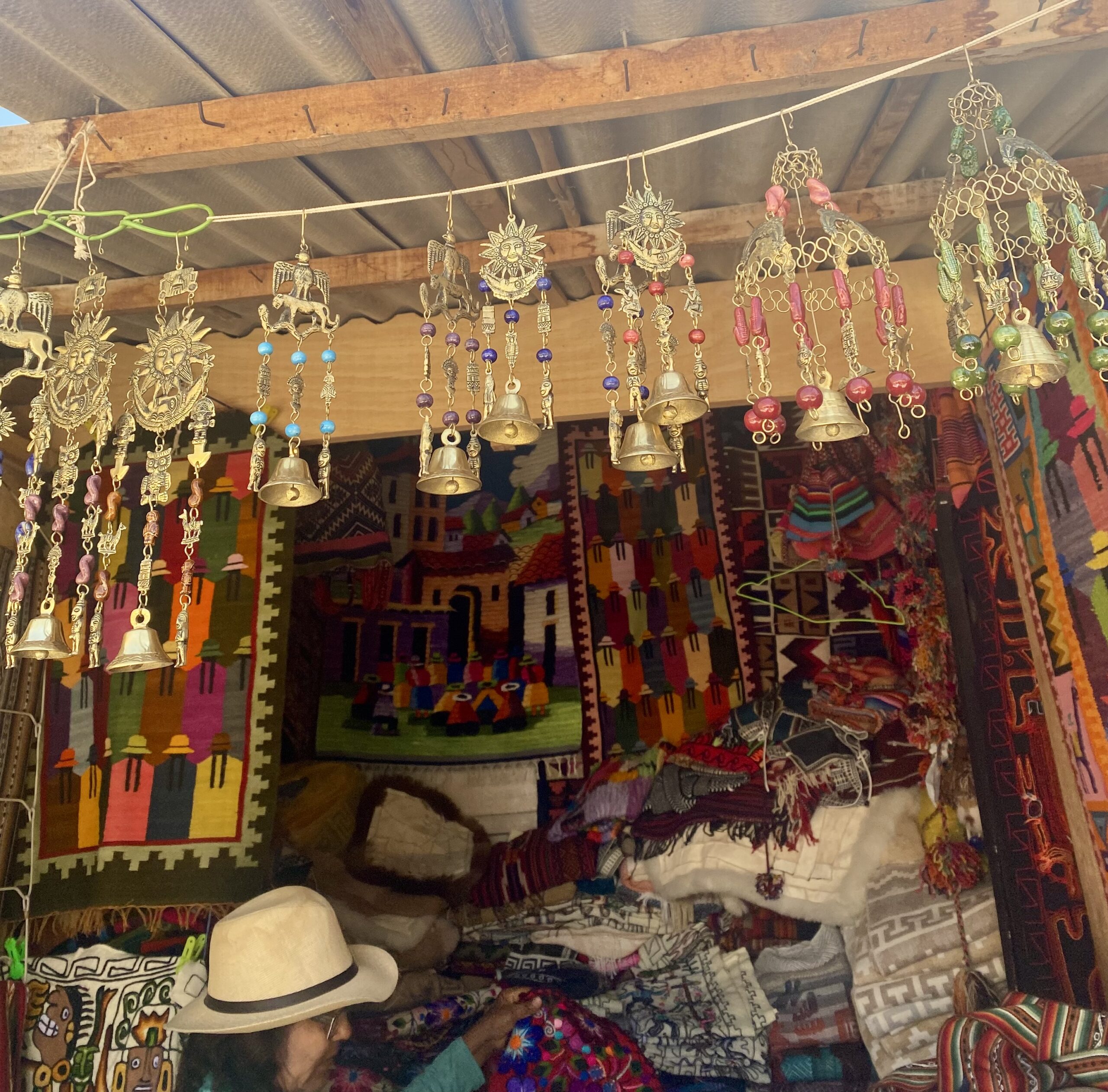 Dettaglio di una bancarella a Ollantaytambo con tessuti tradizionali e campanelle decorative